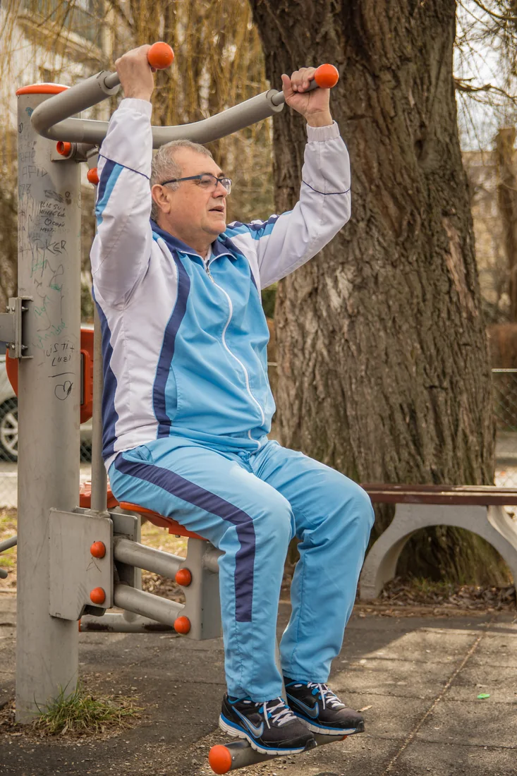 Pacient făcând exerciții la aparatele din parc